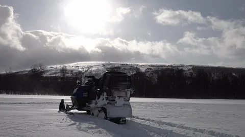 Snowmobile without driver stands in front of white snow field in mountains Stock Footage 130079118