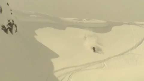 Snowmobiler coming over edge of mountain Video stock 303934748