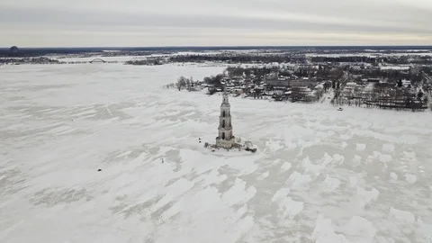 Snowskies gather around an abandoned cathedral amid a frozen river Stock Footage