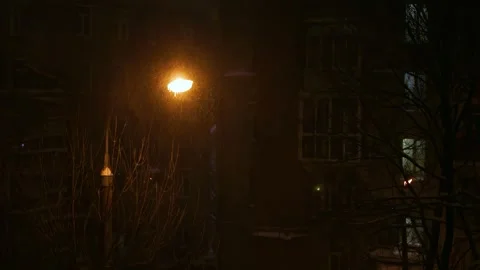 Snowstorm and wind with falling snow under a glowing night lantern in winter Stock Footage 326838247