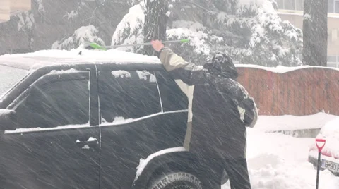 Snowstorm, man removing snow from SUV, car stuck, bad weather in winter Stock Footage 34431990