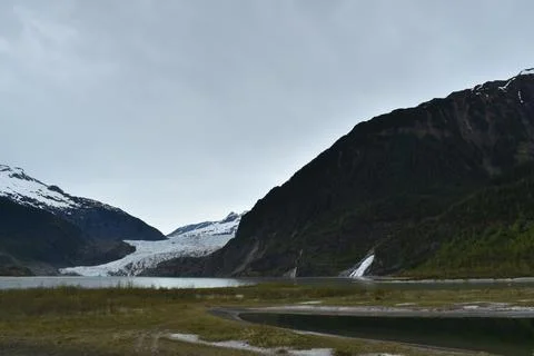 Snowy Alaskan Mountain Peak with grass and trees Stock Photos