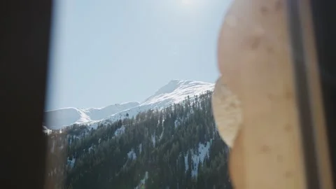 Snowy alpine mountain range with pine forests seen from a rustic wooden cabin on 스톡 동영상 334712354