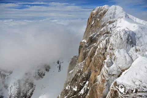 Snowy alpine mountainside with clouds Stock Photos