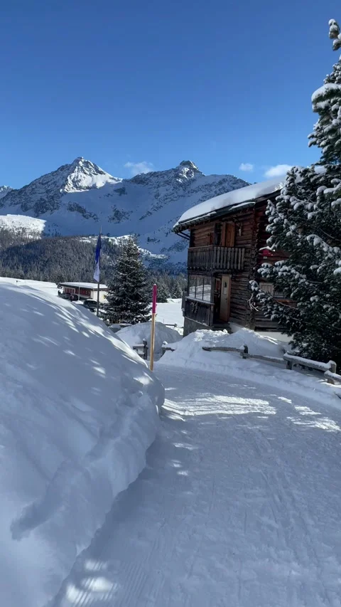 Snowy alpine peaks under a clear blue sky with Swiss chalet Stock Footage 330585322