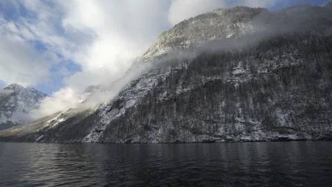 Snowy cloud bound mountains in Bavaria while cruising on pristine lake Stock Footage 120984860