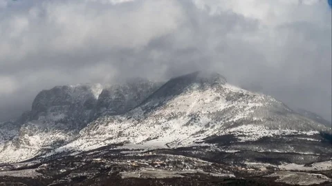 Snowy clouds and sun over the mountains, time lapse Stock Footage 70248971