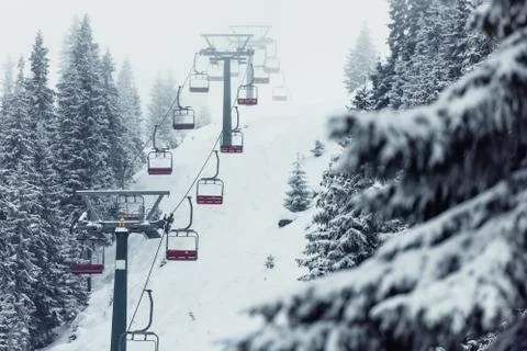 Snowy forest with snowlift, slope, people skiing Stock Photos