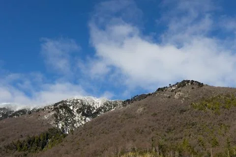Snowy mountain between the clouds and mountainous forest Stock Photos