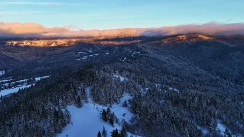 A snowy mountain covered in trees, seen from above, with the sky, clouds Stock-Footage 264647377