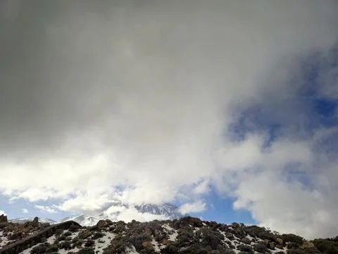 Snowy mountain landscape beneath dramatic cloud cover 库存照片