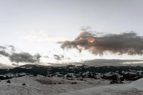 Snowy mountain landscape with dramatic clouds and soft evening light at sunse Stock Photos