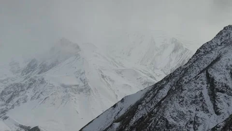Snowy mountain landscape with dramatic peaks, camera pans to reveal depth Video stock 321391615