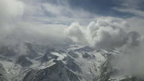 Snowy mountain landscape with dynamic cloud movement, camera pans across scene 库存影片 323297393
