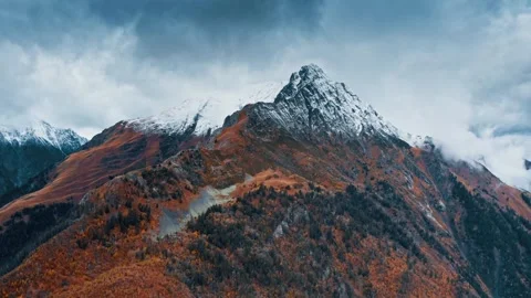 Snowy mountain landscape transitions through autumn colors Stock Footage 320303948