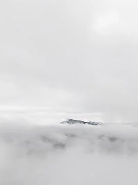 Snowy mountain peak emerging from thick clouds Stock Photos