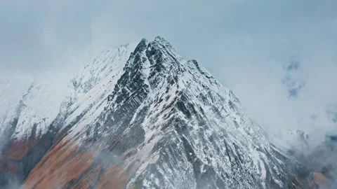 Snowy mountain peaks covered in clouds during morning hours Stock Footage 320304186
