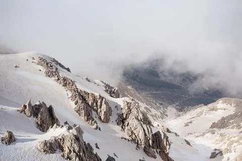 Snowy mountain peaks surrounded with clouds Stock Photos