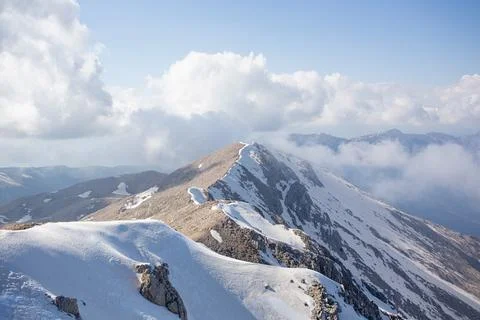 Snowy mountain peaks surrounded with clouds Stock Photos