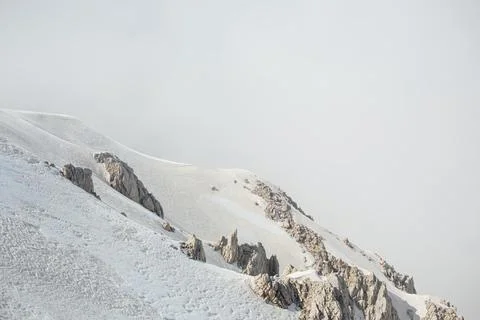 Snowy mountain peaks surrounded with clouds Stock Photos