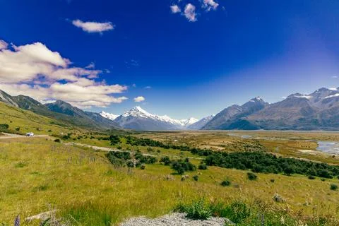 Snowy Mountain Range Above Wide Green Valley Foto stock