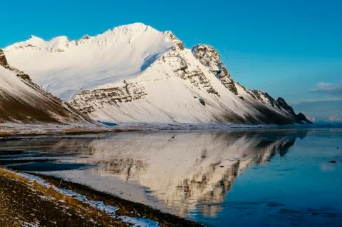 Snowy mountain reflected in still lake in arctic landscape Stock Photos