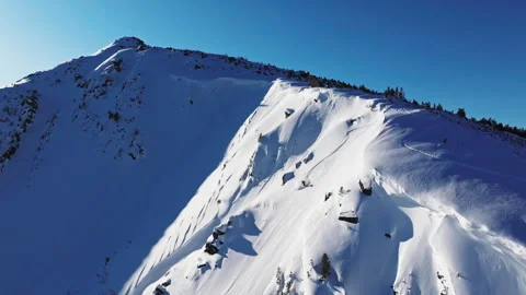Snowy mountain ridge casting long shadows under clear blue sky 動画素材 315003508