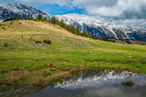 Snowy mountain ridge reflection on the small lake, Carpathians, Romania Stock Photos