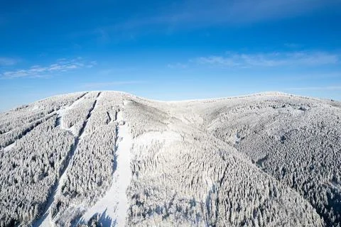 Snowy mountain with ski slope, trees and beautiful sky in winter Stock Photos