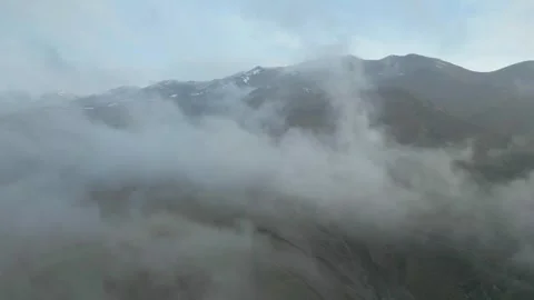 Snowy mountain tops, clouds slowly flying, blue sky. Drone video. Video stock 253773130