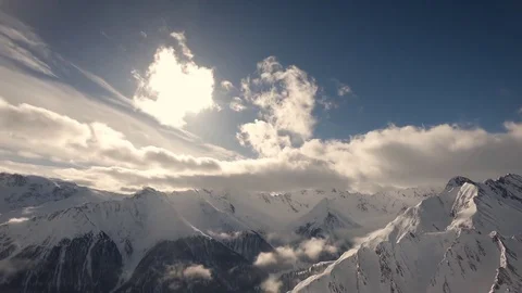 Snowy mountains and clouds time lapse with yellow warm sunlight, cool blue sky Stock Footage 85430236
