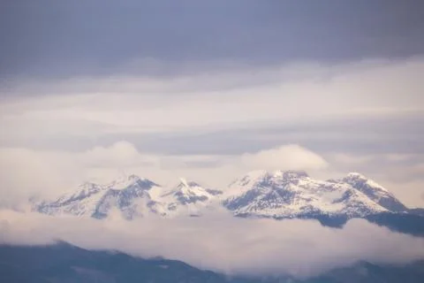 Snowy mountains emerging from the clouds Stock Photos