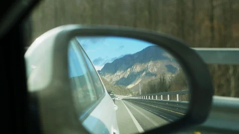Snowy mountains reflected in the rearview mirror while the vehicle is in motion Vídeo Stock 123428708