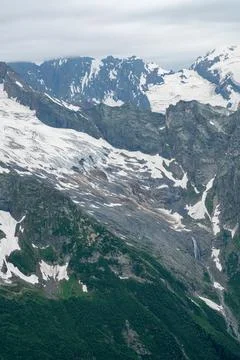 Snowy mountains under cloudy sky in the wilderness Stock Photos