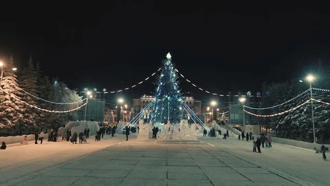Snowy night central square with large glowing Christmas tree. Video stock 81744876