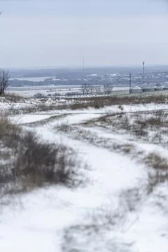 Snowy path winds through field on a cloudy winter day in an open landscape Stock Photos