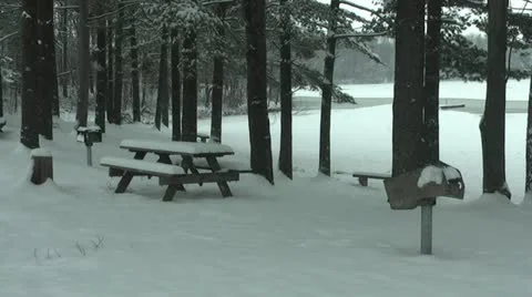 Snowy Picnic Table in Woods Overlooking Frozen Lake Stock Footage 18178646