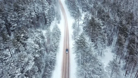 On a snowy road car rides in the middle of a winter frozen forest. The drone Stock Footage 101657402