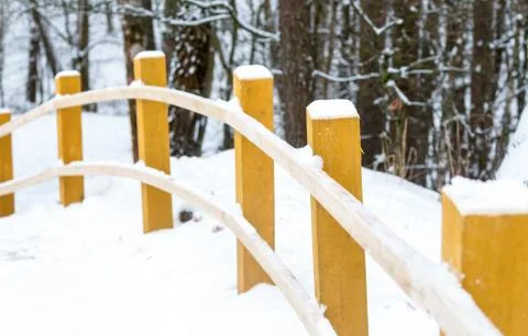 Snowy road forest walk yellow wooden pillars bent curtain railings Stock Photos