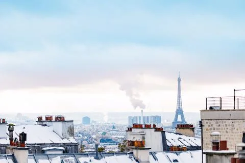 Snowy rooftops with Eiffel Tower in Paris winter sunset skyline Stock Photos
