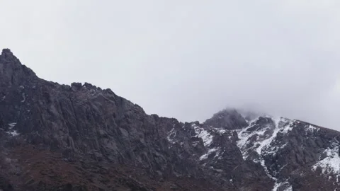 Snowy rugged mountain range under an overcast sky Stock Footage 318359561