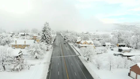 Snowy small town along main street to fog bank-Aerial Stock Footage 99257577