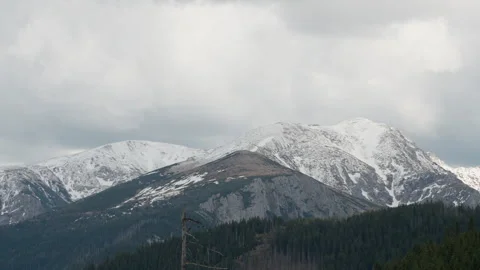 Snowy Tatra mountain peaks panoramic view with pine forest under cloudy sky Stock Footage 335128545