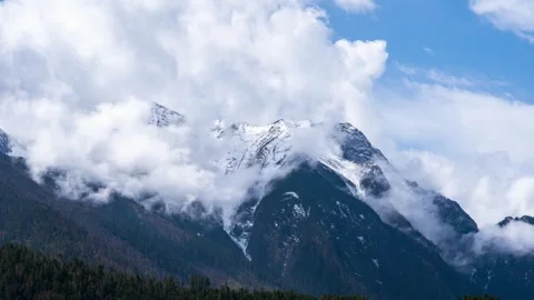 Snowy Tibetan mountain range above forests and rolling clouds Vídeo Stock 345882601
