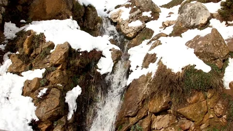 Snowy waterfall down the mountain . snow Dissolves into waterfall Stock Footage 130460300