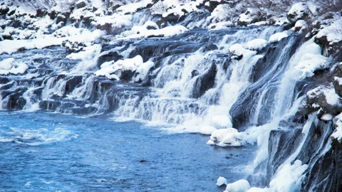 Snowy waterfall at winter. Mountain river with pure glacier water in 8k. Iceland Stock Footage 234072483