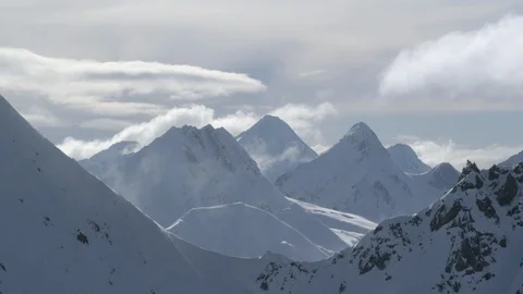 Snowy winter mountains with clouds moving in sky during day time Stock Footage 121575879