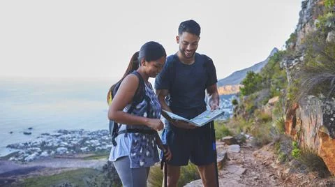 This is so helpful to plot out our hike path. Shot of a young couple using a  Fotos de archivo