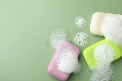 Soap bars with foam on green background, flat lay. Space for text Stock Photos