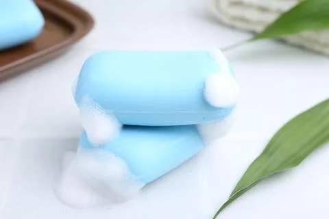 Soap bars with foam on white table, closeup 스톡 사진